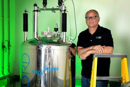 Salk Professor Joseph Noel, pictured in his lab, next to an NMR spectroscopy machine, which is used to decipher the detail of the electronic structures of molecules.